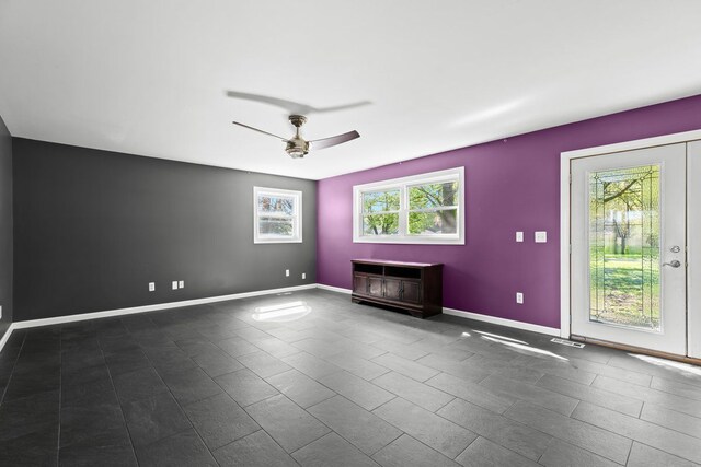 unfurnished room with baseboards, a ceiling fan, and dark tile patterned flooring
