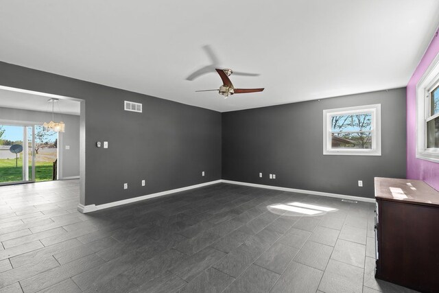 spare room featuring baseboards, a wealth of natural light, ceiling fan with notable chandelier, and visible vents