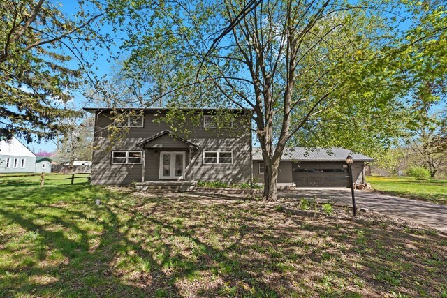 view of front of property featuring an attached garage, driveway, french doors, and a front lawn