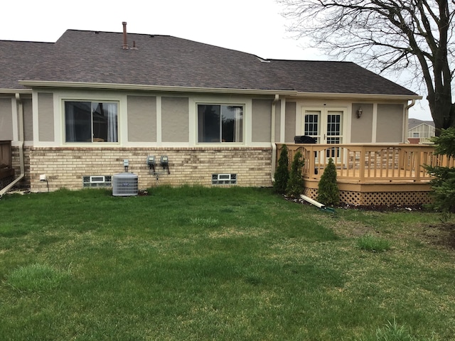 rear view of property with central air condition unit, a wooden deck, a yard, and brick siding