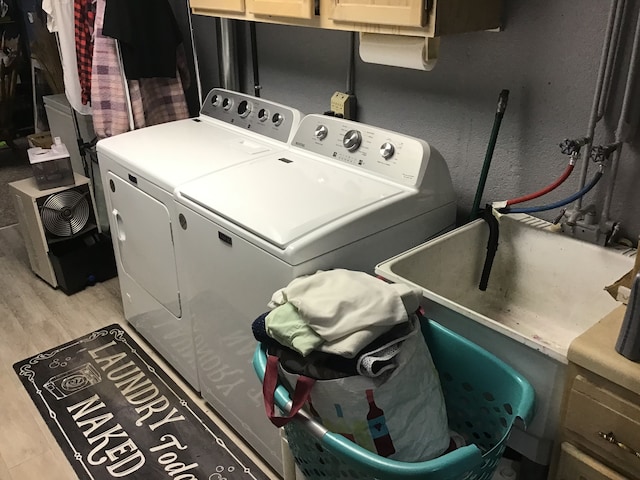 laundry room with independent washer and dryer, cabinet space, and light wood-type flooring
