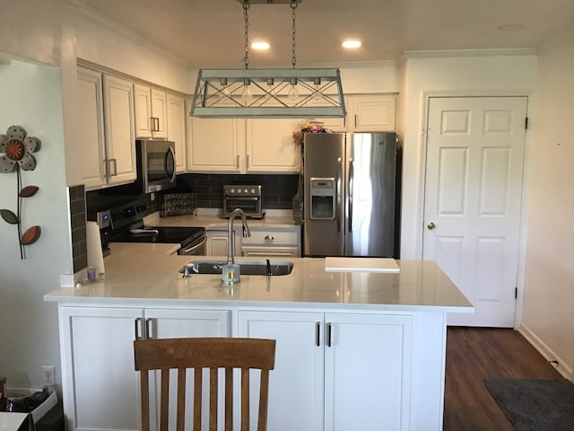 kitchen featuring decorative backsplash, appliances with stainless steel finishes, a sink, light countertops, and a peninsula