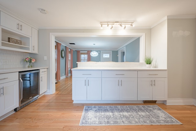 bathroom with backsplash, crown molding, wood finished floors, baseboards, and beverage cooler