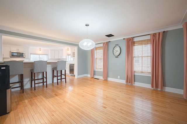 interior space featuring baseboards, a chandelier, and light wood-style flooring