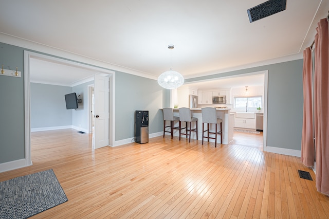 dining space featuring visible vents, light wood finished floors, crown molding, and baseboards