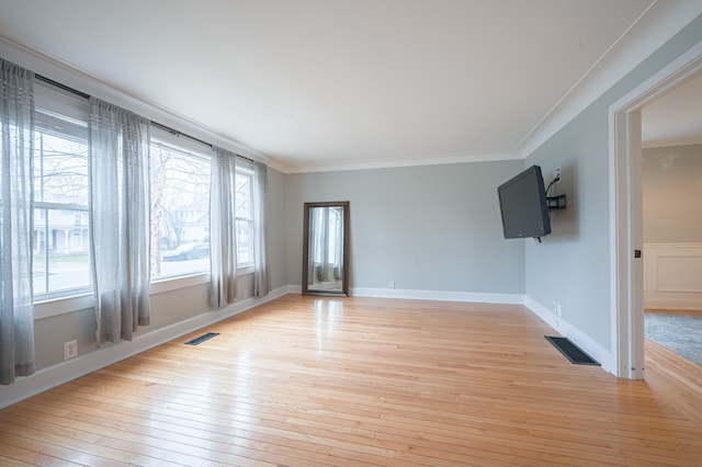 spare room featuring plenty of natural light, ornamental molding, and light wood-style floors