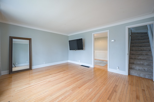 unfurnished living room with visible vents, crown molding, light wood-type flooring, stairway, and baseboards