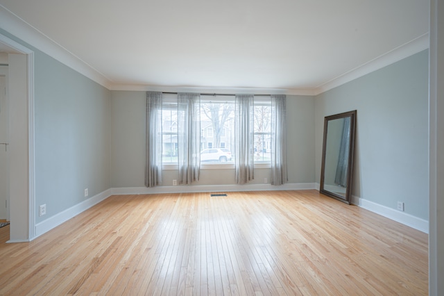 spare room featuring crown molding, light wood-style flooring, baseboards, and visible vents
