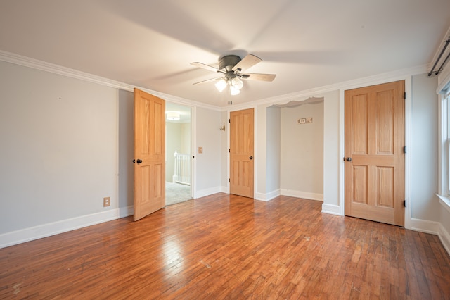 empty room with crown molding, baseboards, ceiling fan, and wood-type flooring