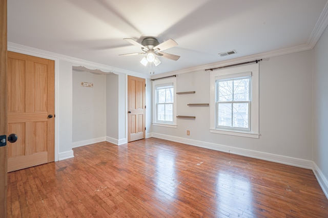 empty room featuring visible vents, ornamental molding, hardwood / wood-style floors, baseboards, and a ceiling fan