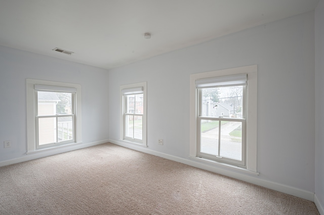 spare room featuring visible vents, baseboards, and light colored carpet