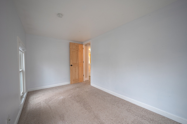 unfurnished room featuring baseboards and light colored carpet