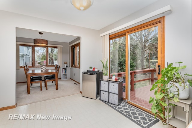 dining area with baseboards, a healthy amount of sunlight, and light colored carpet