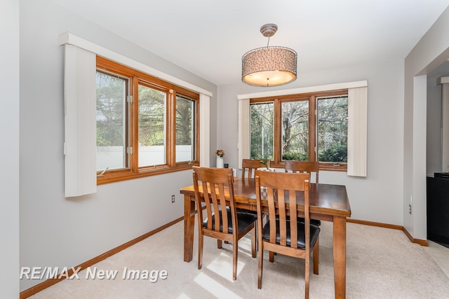 dining space with baseboards and light carpet