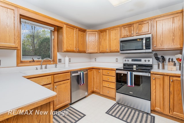 kitchen featuring brown cabinetry, light floors, light countertops, a sink, and stainless steel appliances