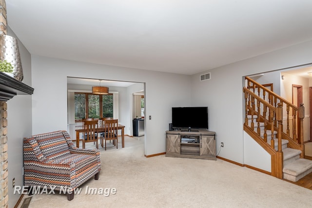 carpeted living area with visible vents, stairs, and baseboards