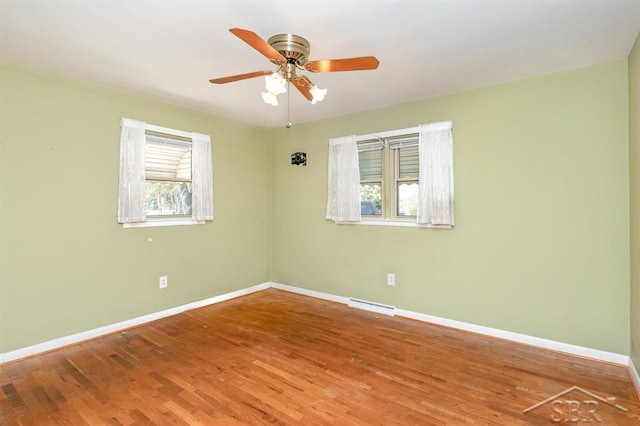 unfurnished room with baseboards, ceiling fan, wood finished floors, and visible vents