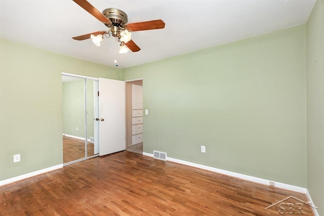 unfurnished bedroom with visible vents, a ceiling fan, baseboards, and wood finished floors