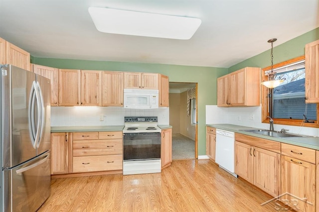 kitchen with a sink, light brown cabinets, light wood-style floors, and white appliances
