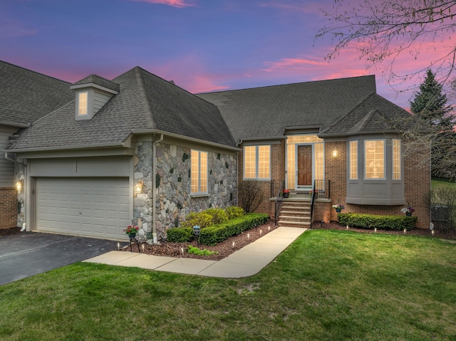 view of front of property featuring a front yard, brick siding, a shingled roof, an attached garage, and driveway