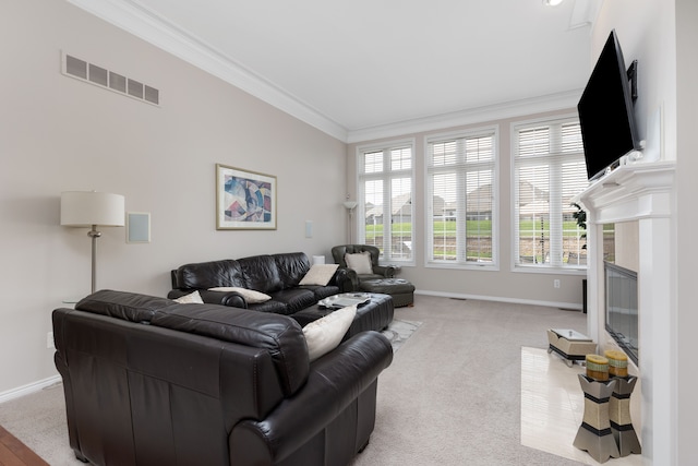 living area featuring visible vents, ornamental molding, light carpet, a fireplace, and baseboards