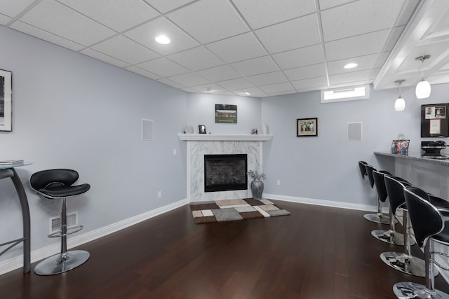 living area featuring visible vents, wood finished floors, baseboards, recessed lighting, and a premium fireplace
