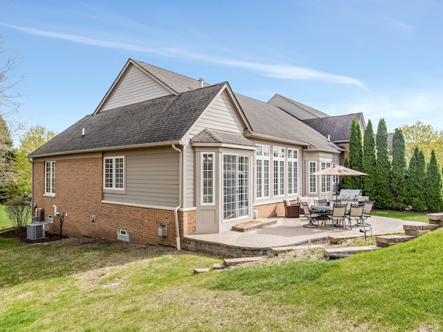back of property with roof with shingles, central AC, brick siding, a lawn, and a patio