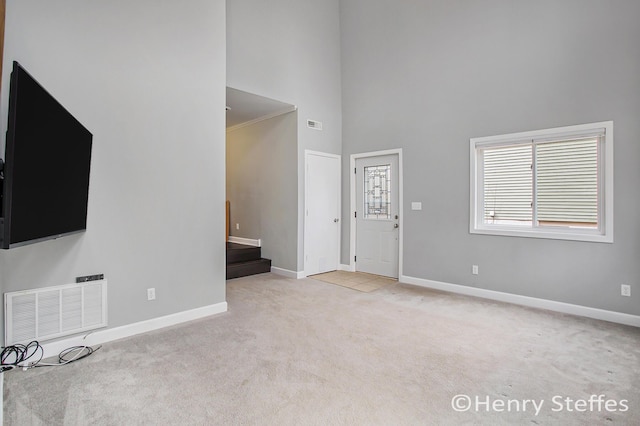 1355 Middle Ln, Battle Creek, MI 49014 - unfurnished living room with carpet flooring, a high ceiling, and stairway