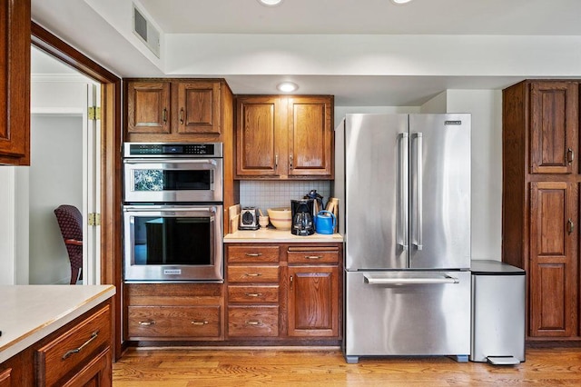 kitchen with visible vents, light wood-style floors, light countertops, tasteful backsplash, and stainless steel appliances