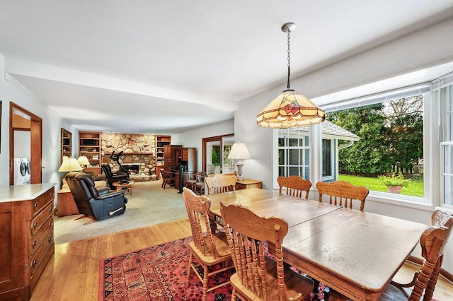dining space featuring washing machine and clothes dryer, built in features, a fireplace, and light wood-type flooring