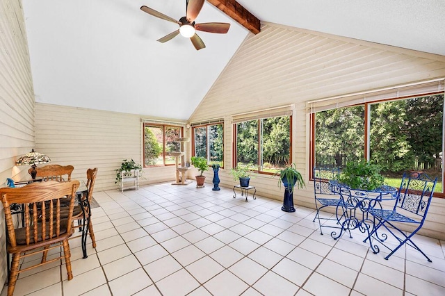 sunroom / solarium with beamed ceiling, wooden walls, and tile patterned floors