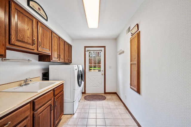 washroom with light tile patterned flooring, baseboards, separate washer and dryer, a sink, and cabinet space