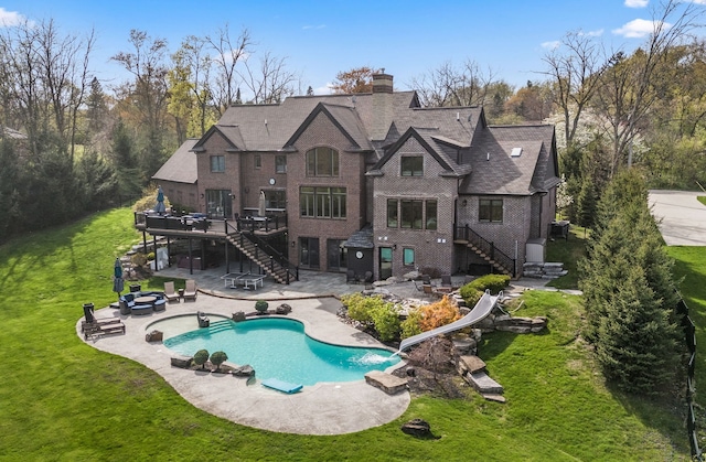back of house with a wooden deck, a patio, stairs, an outdoor fire pit, and a yard