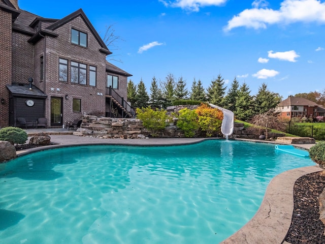 view of pool featuring a fenced in pool, a water slide, stairway, and fence