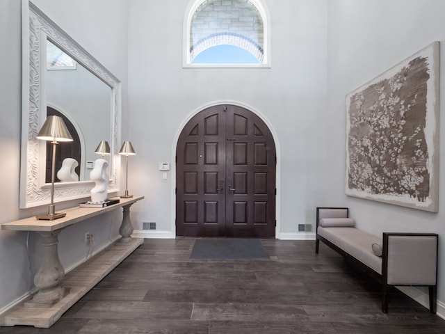 foyer featuring visible vents, plenty of natural light, a towering ceiling, and wood finished floors