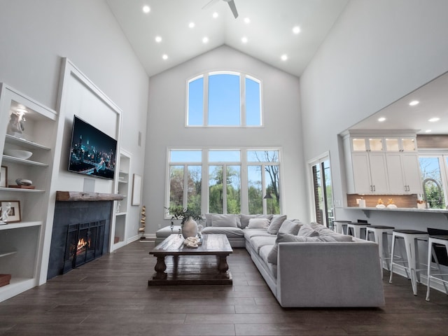 living area with recessed lighting, high vaulted ceiling, a lit fireplace, and dark wood-style floors