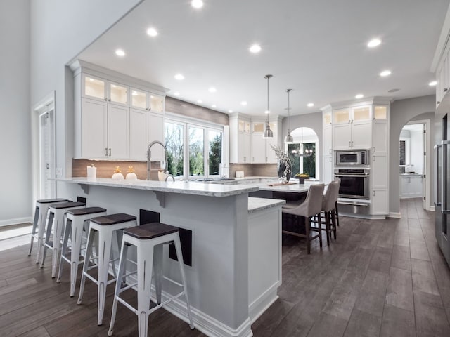 kitchen featuring recessed lighting, arched walkways, a kitchen breakfast bar, and stainless steel appliances