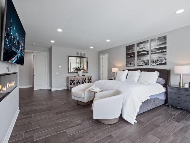bedroom with baseboards, recessed lighting, wood finished floors, and visible vents