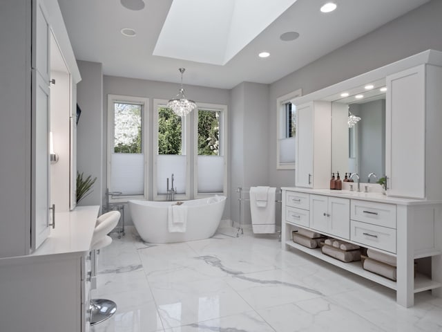full bathroom featuring an inviting chandelier, a freestanding bath, vanity, recessed lighting, and a skylight