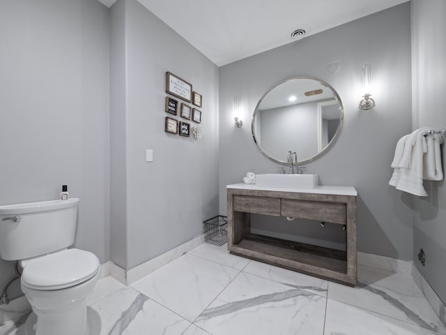 bathroom with vanity, toilet, marble finish floor, baseboards, and visible vents