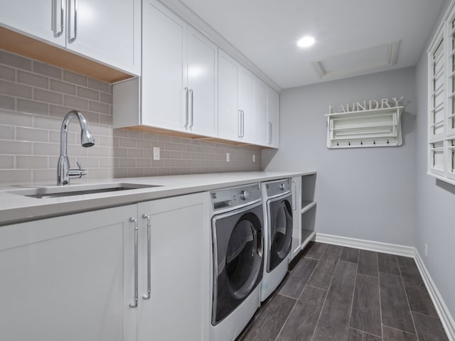 washroom featuring washer and dryer, baseboards, dark wood-type flooring, a sink, and cabinet space