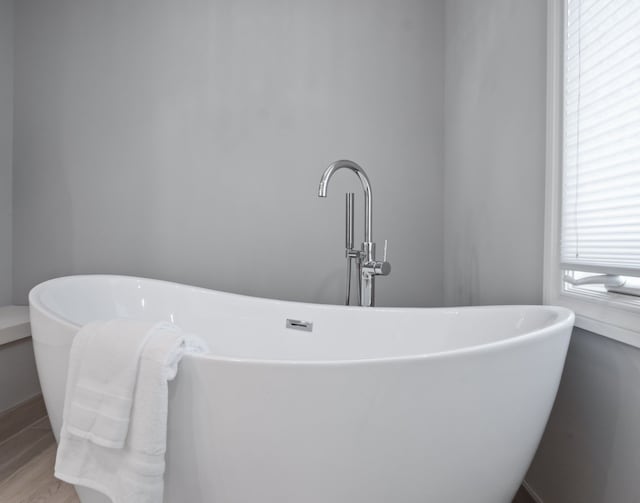 bathroom with a freestanding bath, a sink, and wood finished floors