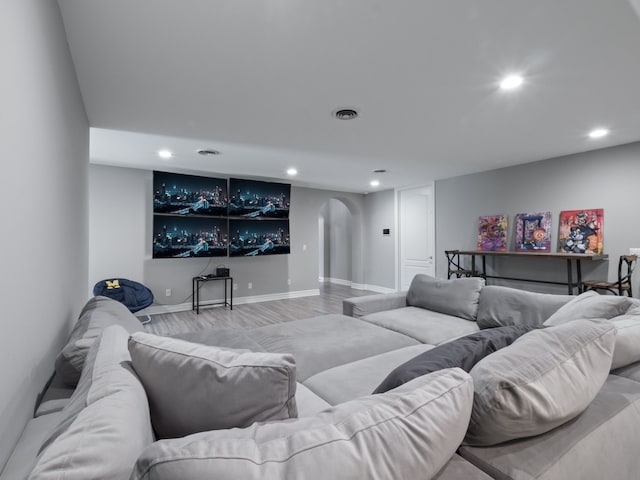 living area featuring recessed lighting, arched walkways, and wood finished floors