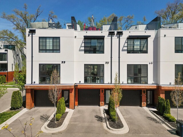 back of house featuring stucco siding, driveway, and a garage