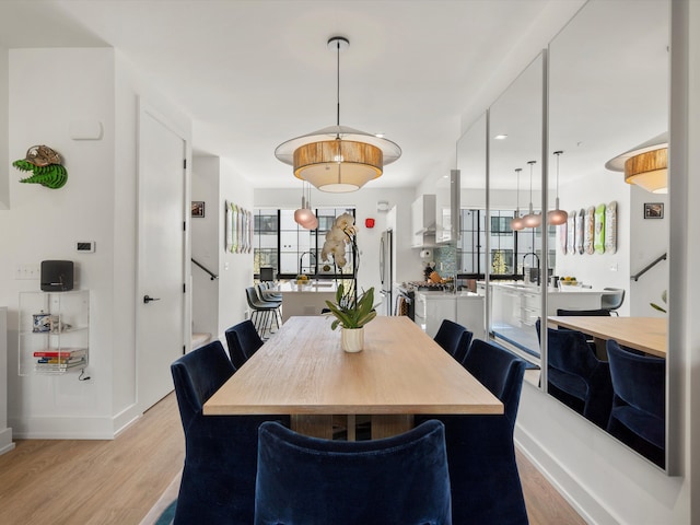 dining space with baseboards, plenty of natural light, stairway, and light wood-style floors