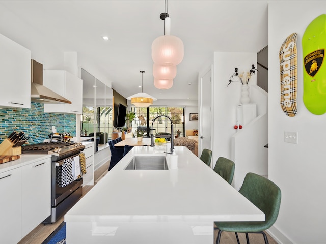 kitchen featuring a sink, a kitchen bar, stainless steel range with gas cooktop, and white cabinetry
