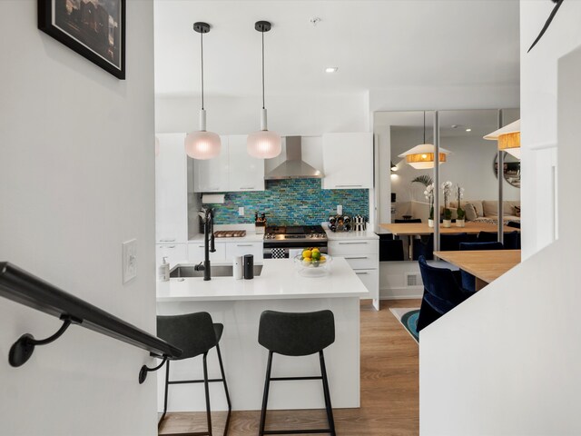 kitchen with wall chimney range hood, modern cabinets, a sink, stainless steel gas range, and white cabinetry