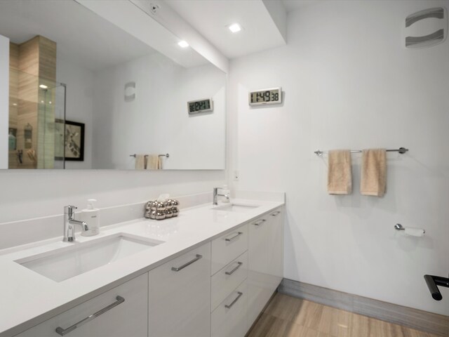 bathroom featuring double vanity, recessed lighting, a sink, and a stall shower
