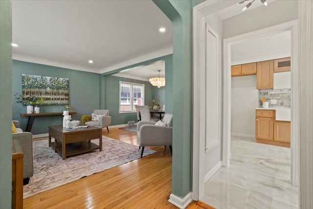 living room featuring recessed lighting, baseboards, a chandelier, and light wood-style floors