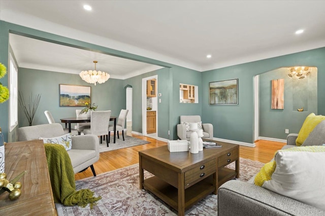 living area featuring an inviting chandelier, wood finished floors, baseboards, recessed lighting, and arched walkways